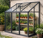 Glass greenhouse with plants inside against a brick wall