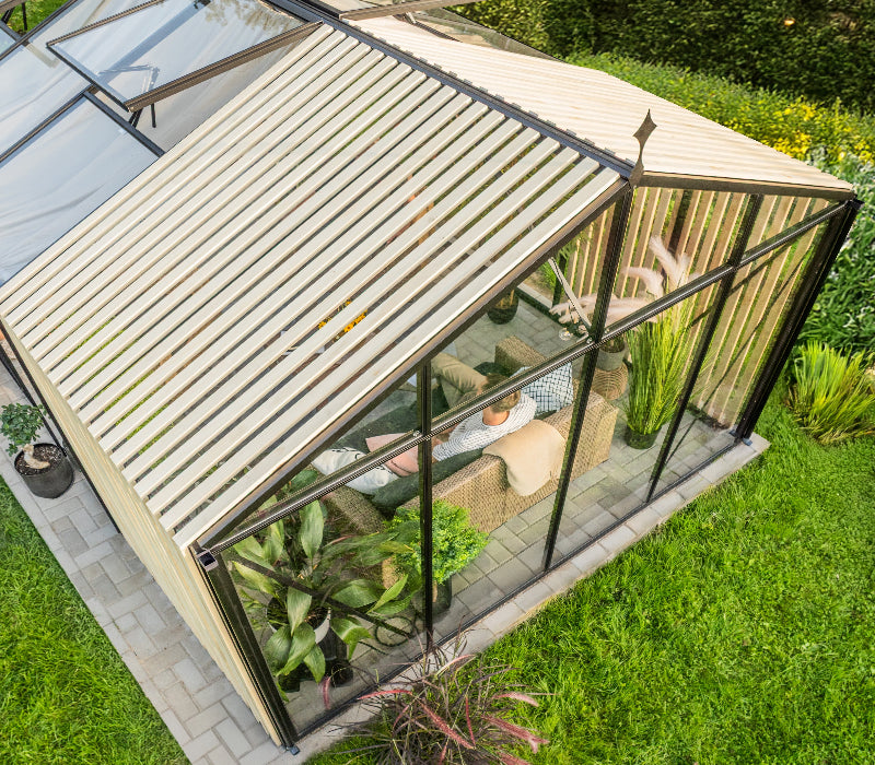 Garden room with glass walls and wooden roof, surrounded by greenery