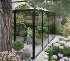 Black framed greenhouse in a garden with flowers and plants