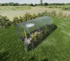 Clear greenhouse on a grassy field with trees in the background